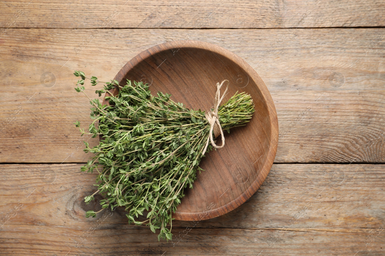 Photo of Bunch of aromatic thyme on wooden table, top view