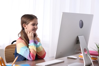 E-learning. Cute girl using computer during online lesson at table indoors