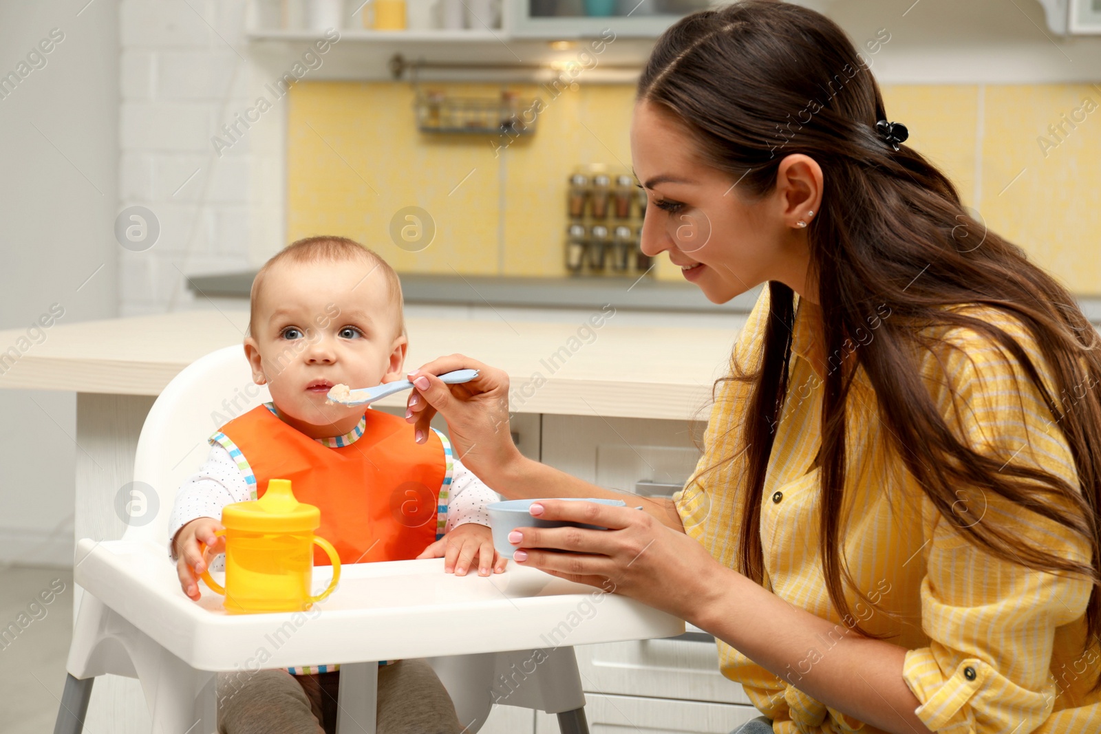 Photo of Young mother feeding her little baby at home