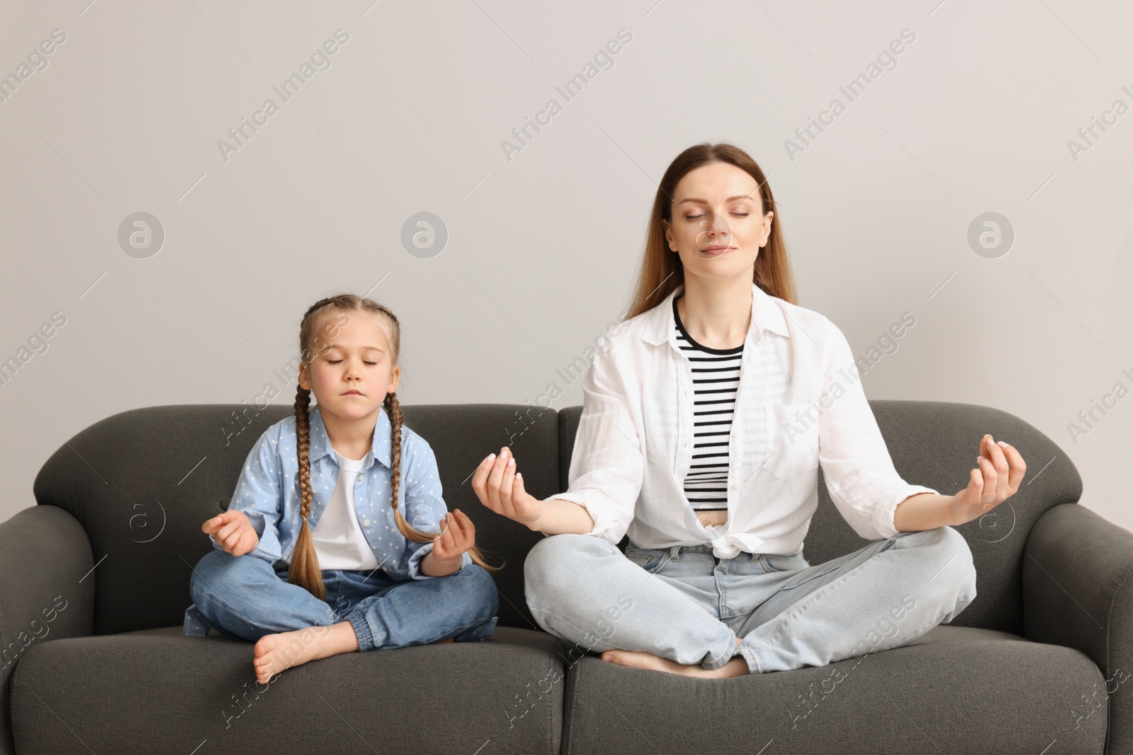 Photo of Mother with daughter meditating together at home. Harmony and zen