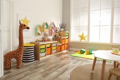 Photo of Stylish playroom interior with shelving unit and different soft toys