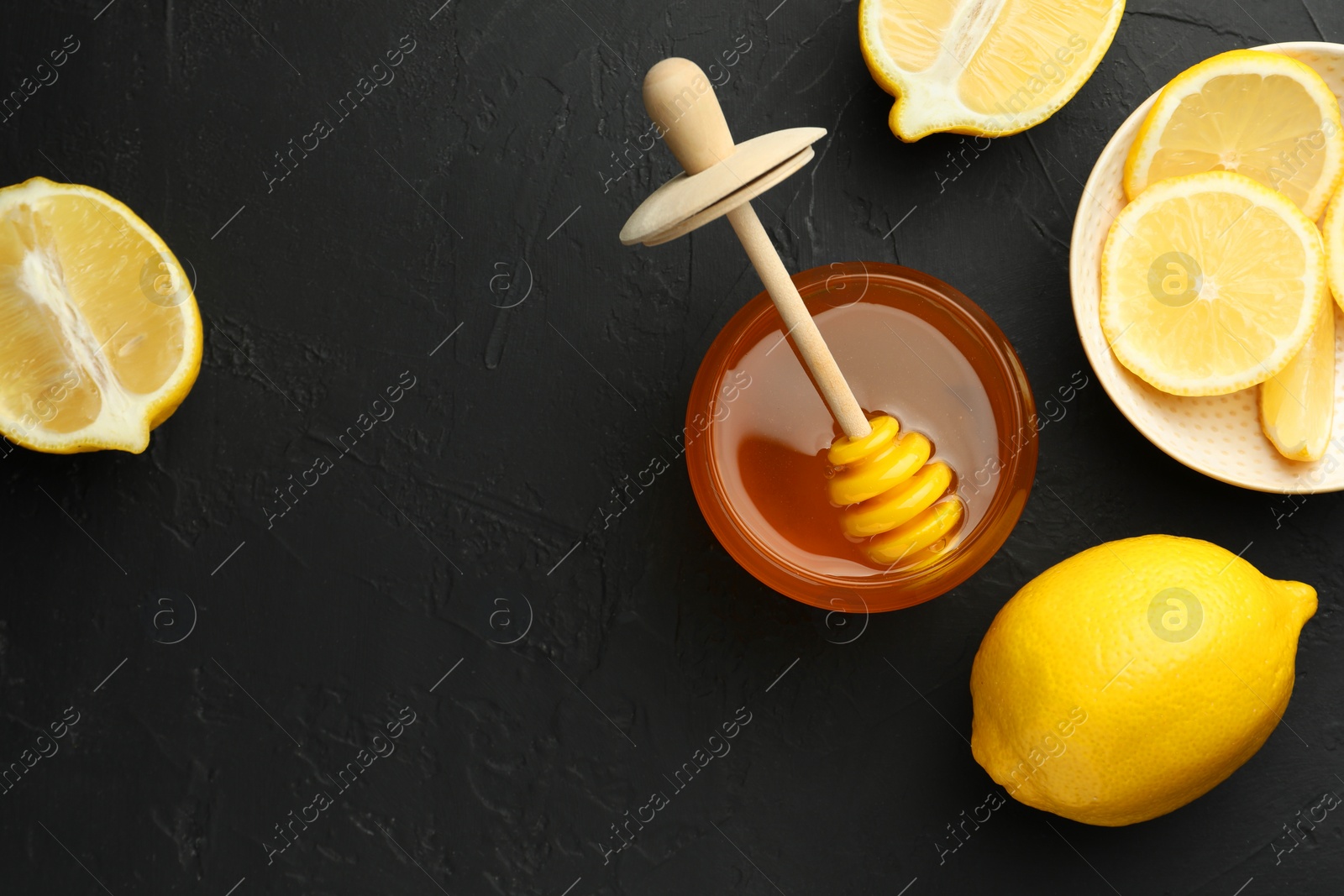 Photo of Sweet honey and fresh lemons on black table, flat lay. Space for text