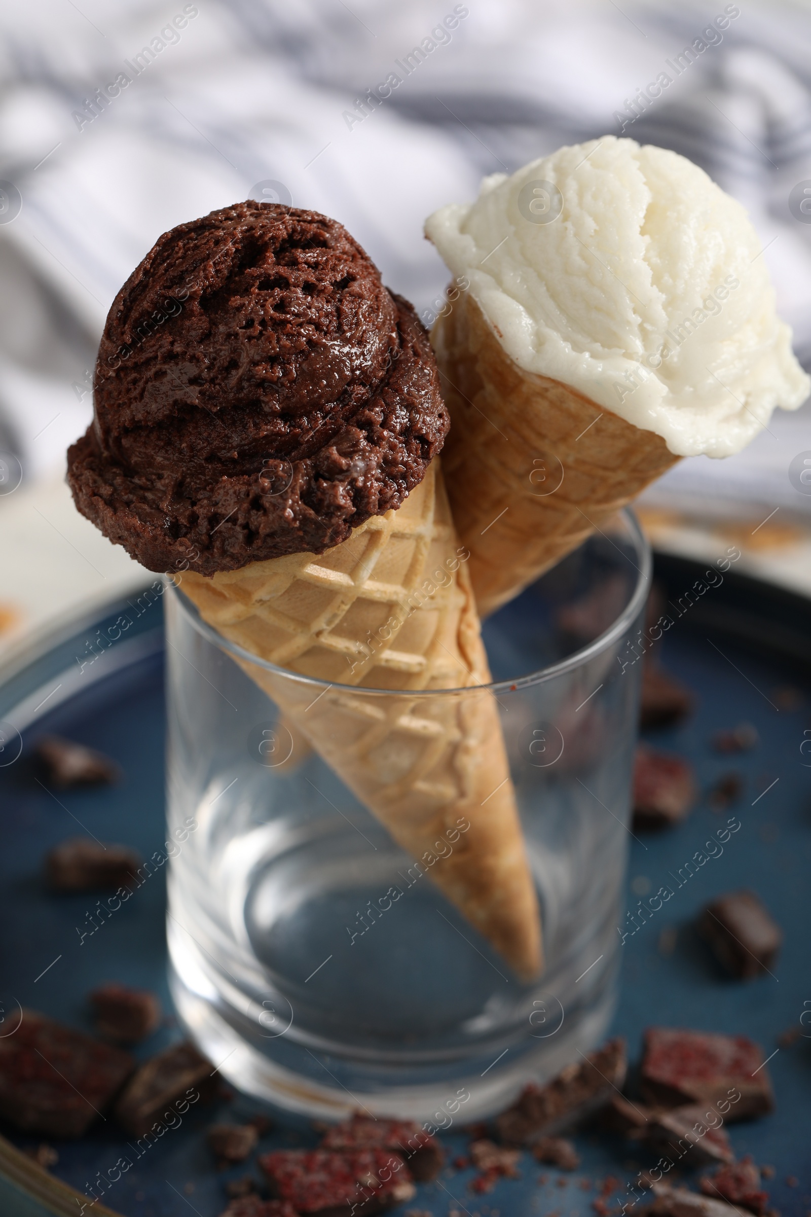 Photo of Tasty ice cream scoops in waffle cones and chocolate crumbs on table, closeup