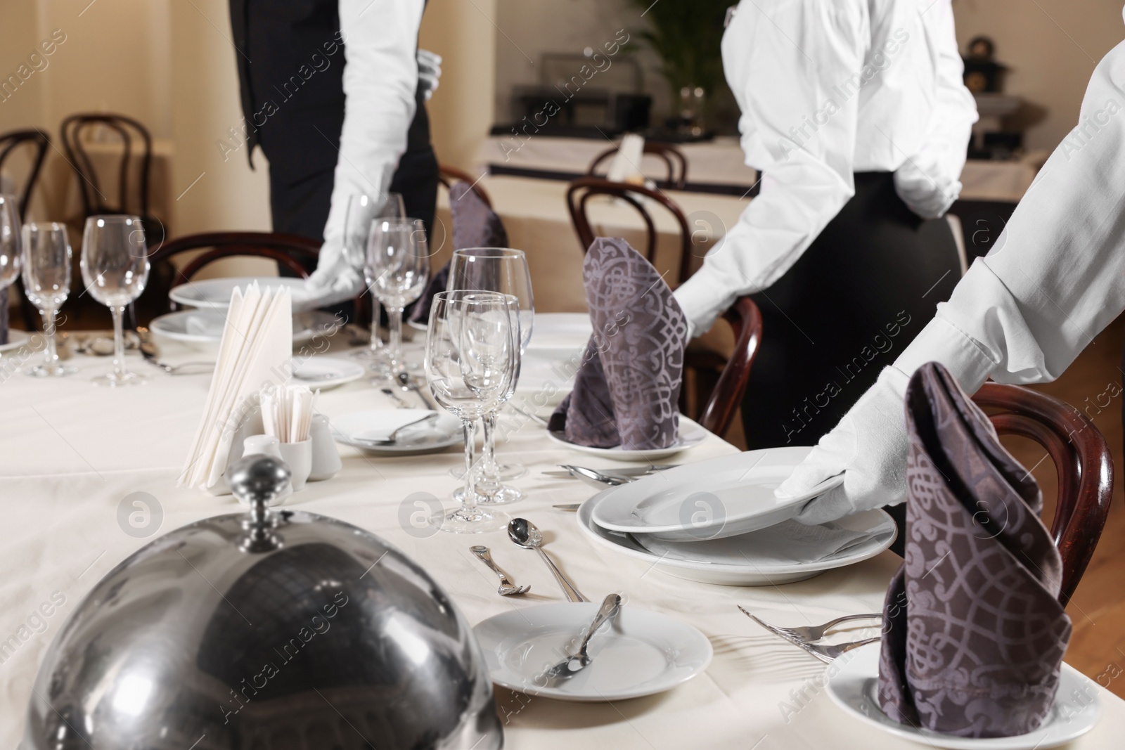 Photo of People setting table during professional butler courses in restaurant, closeup