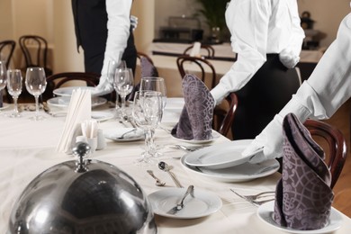 Photo of People setting table during professional butler courses in restaurant, closeup