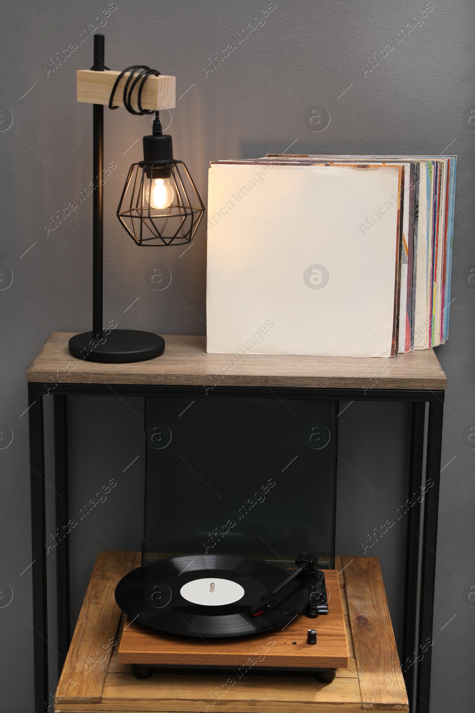 Photo of Stylish turntable with vinyl disc on wooden crate in room