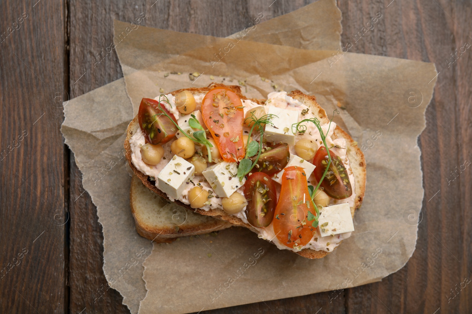 Photo of Tasty vegan sandwich with tomatoes, tofu and chickpeas on wooden table, top view