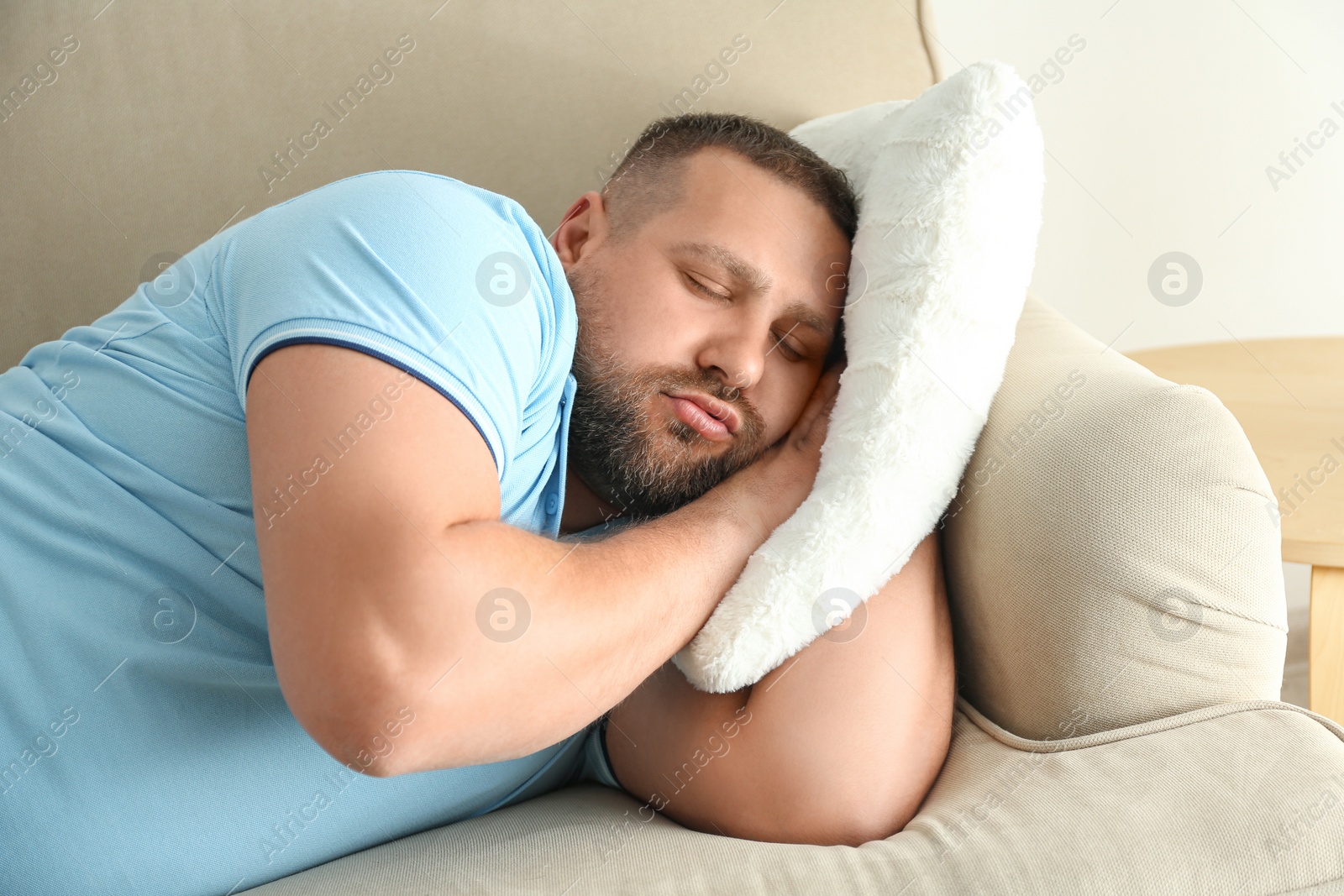 Photo of Lazy overweight man sleeping on sofa at home