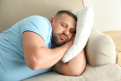 Photo of Lazy overweight man sleeping on sofa at home