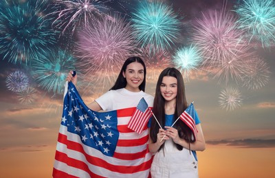 Image of 4th of July - Independence day of America. Happy mother and daughter holding national flags of United States against sky with fireworks