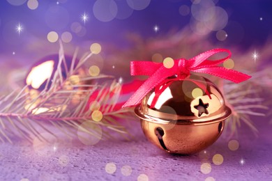 Golden sleigh bells and fir branches on table, closeup