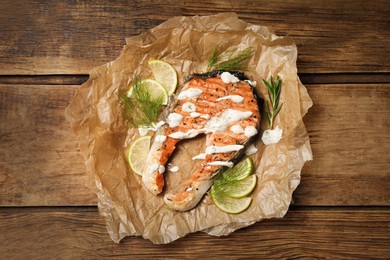 Photo of Tasty salmon steak with sauce, citrus slices and herbs on wooden table, top view