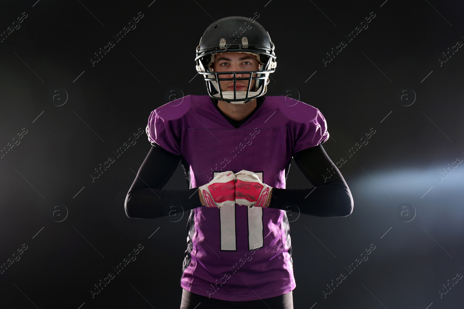 Photo of American football player wearing uniform on dark background