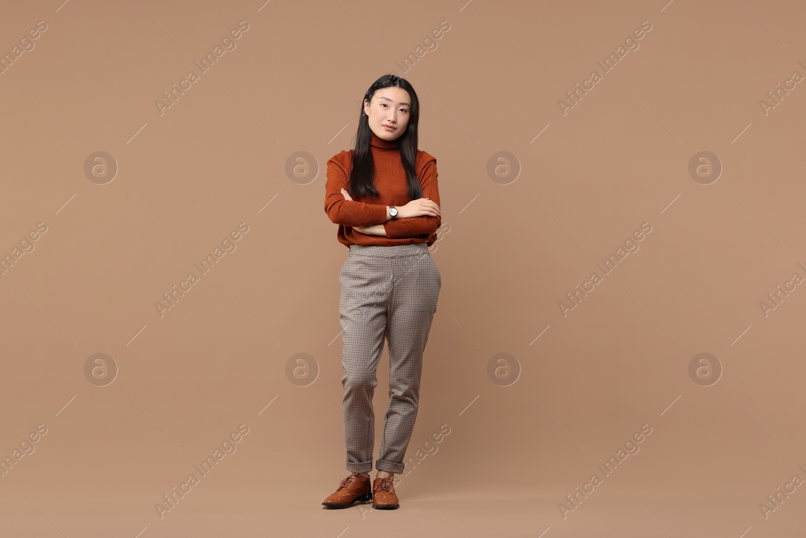 Photo of Full length portrait of beautiful woman with crossed arms on brown background