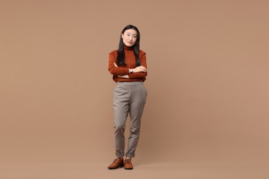 Photo of Full length portrait of beautiful woman with crossed arms on brown background