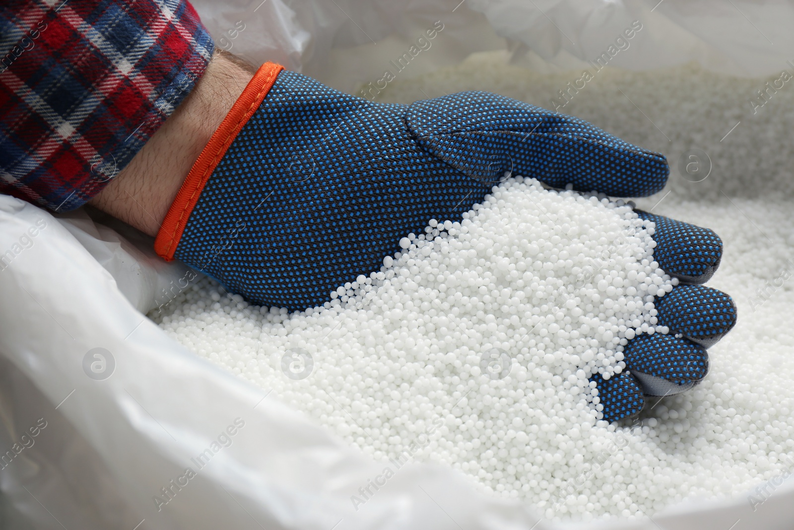 Photo of Farmer taking pellets of ammonium nitrate from bag, closeup. Mineral fertilizer