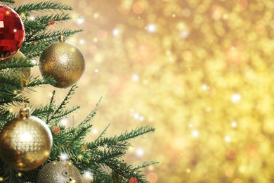 Image of Beautiful Christmas tree with bright baubles on blurred golden background, closeup. Space for text