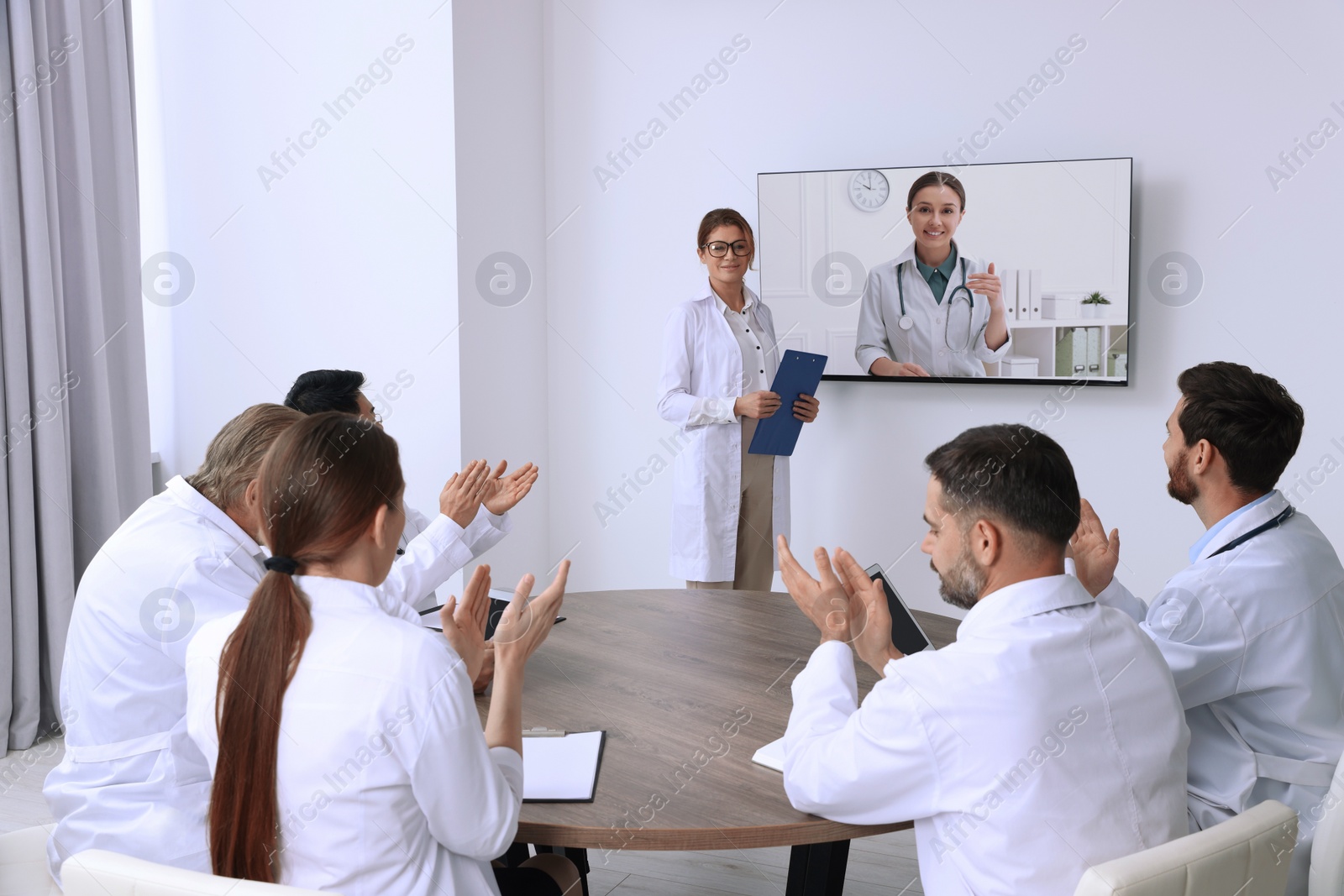 Image of Lecture with online participant. Doctors in meeting room. Using tv for videoconference