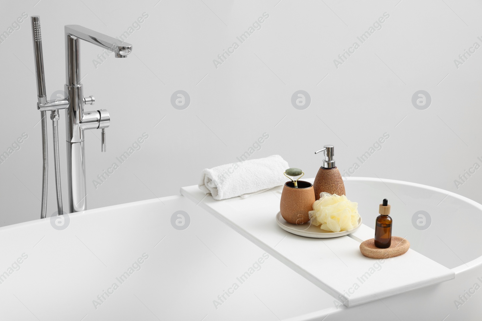 Photo of Different personal care products and accessories on bath tub in bathroom, space for text