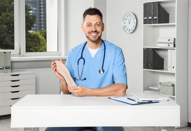 Handsome male orthopedist showing insole in hospital