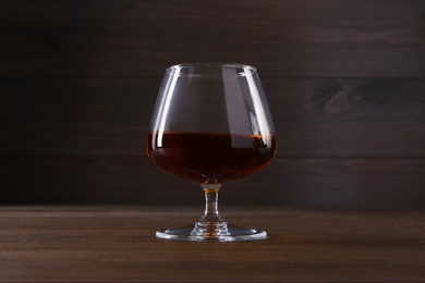 Delicious liqueur in glass on wooden table