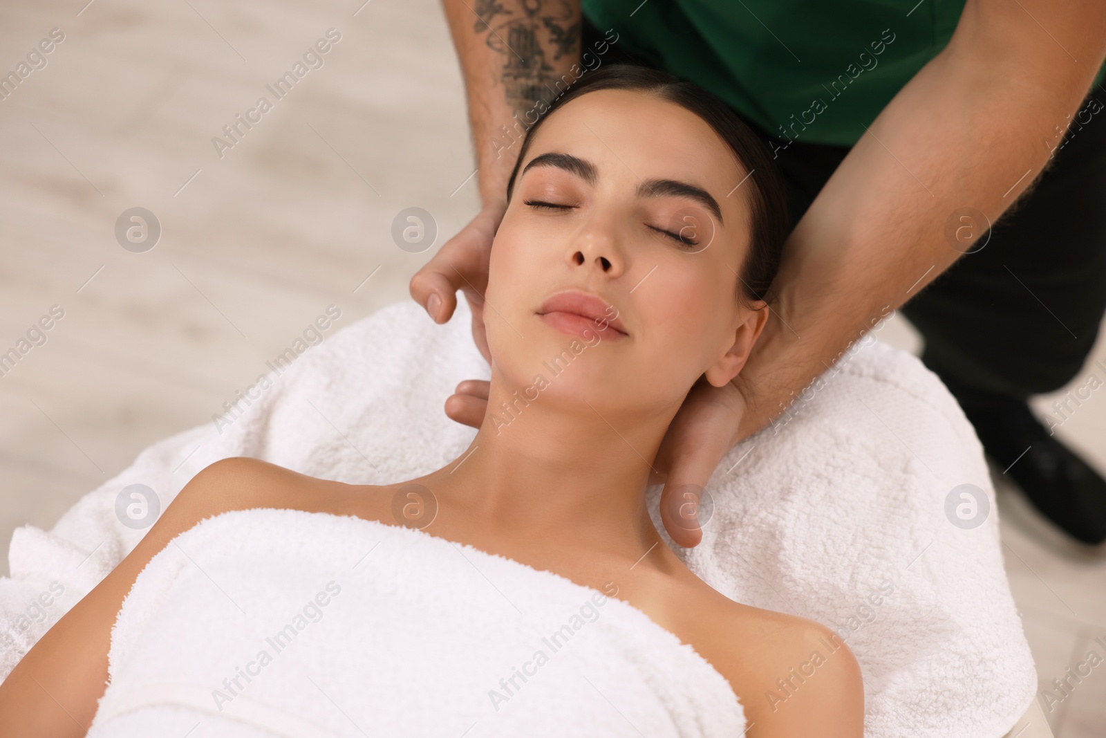 Photo of Woman receiving professional neck massage on couch indoors