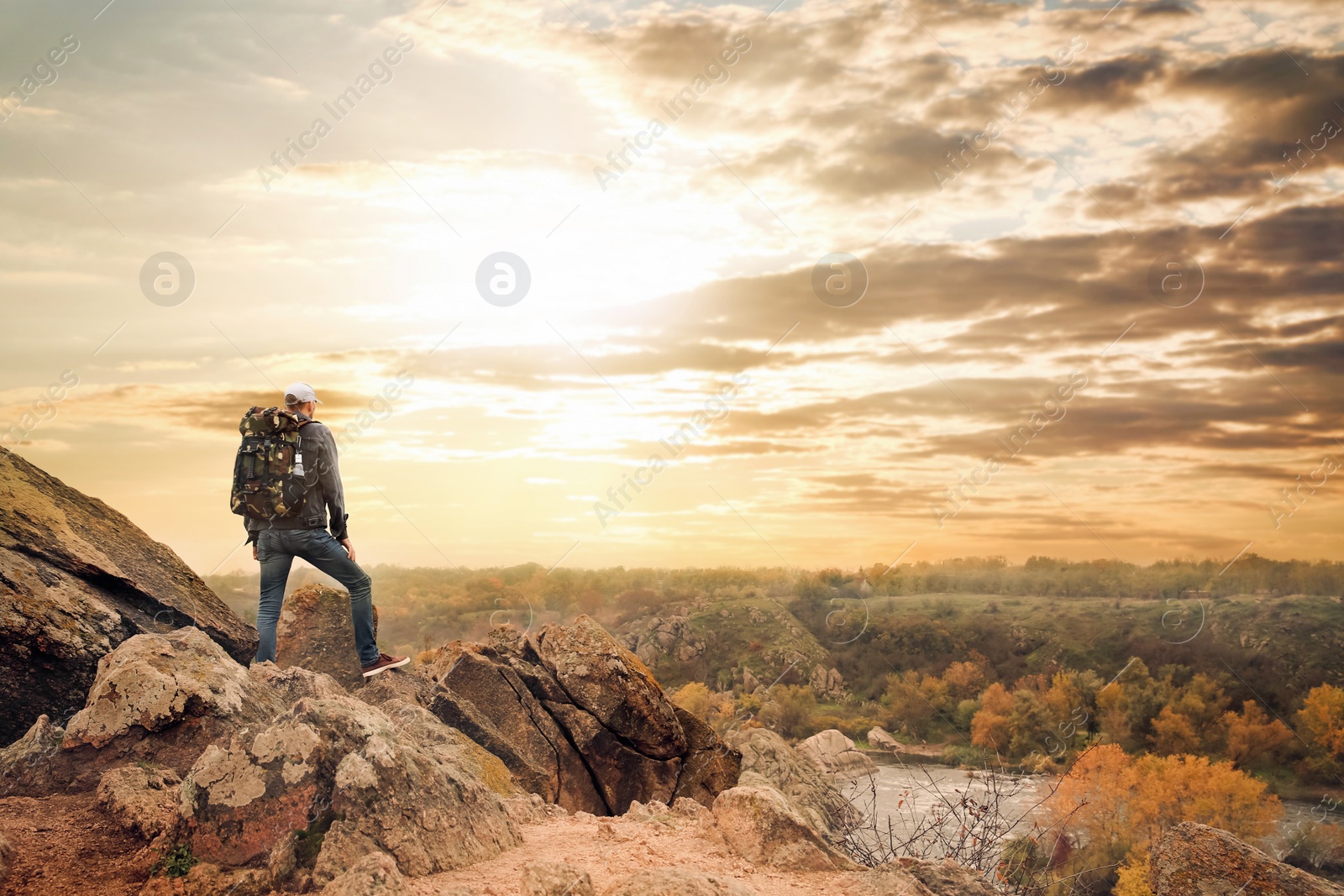 Photo of Hiker with travel backpack enjoying beautiful view near mountain river, back view