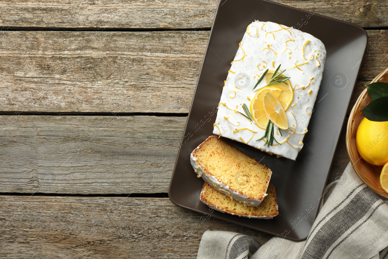 Photo of Tasty lemon cake with glaze and citrus fruits on wooden table, flat lay. Space for text