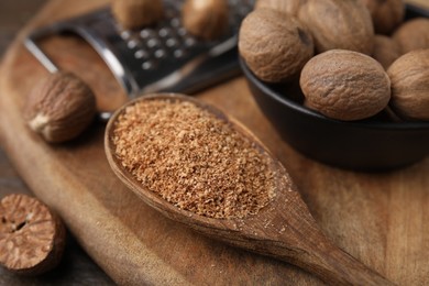 Photo of Spoon with grated nutmeg, seeds and grater on table, closeup