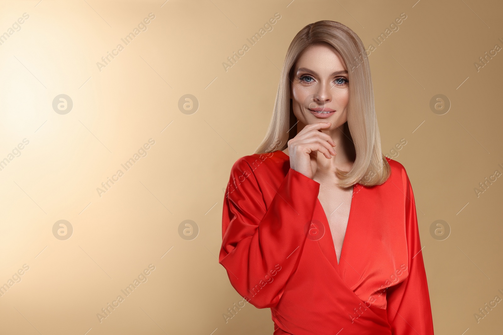 Image of Portrait of stylish attractive woman with blonde hair on dark beige background, space for text