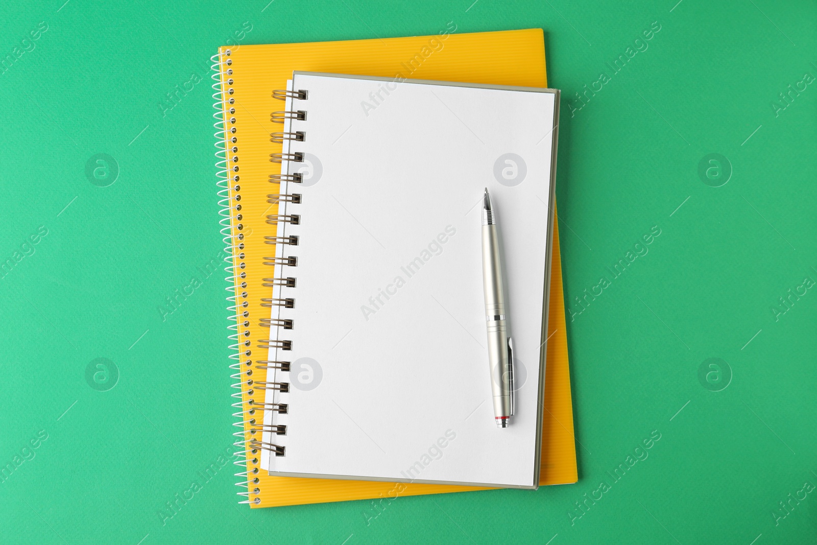 Photo of Notebooks and pen on green background, top view