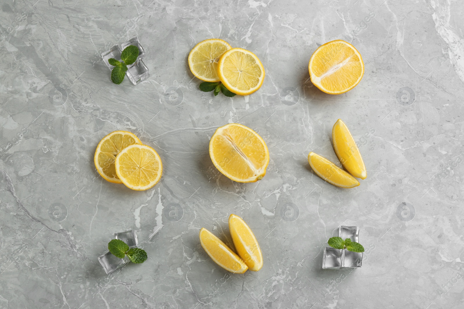 Photo of Lemonade layout with juicy lemon slices, mint and ice cubes on grey marble table, top view