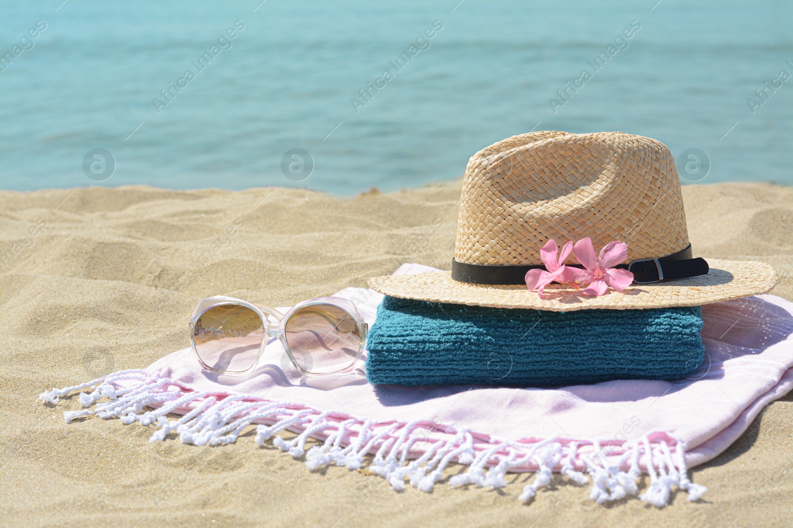Photo of Stylish beach accessories and flowers on sand near sea