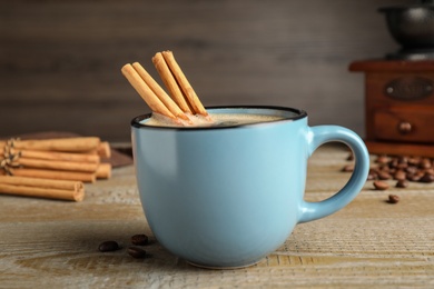 Cup of hot coffee with aromatic cinnamon on wooden table