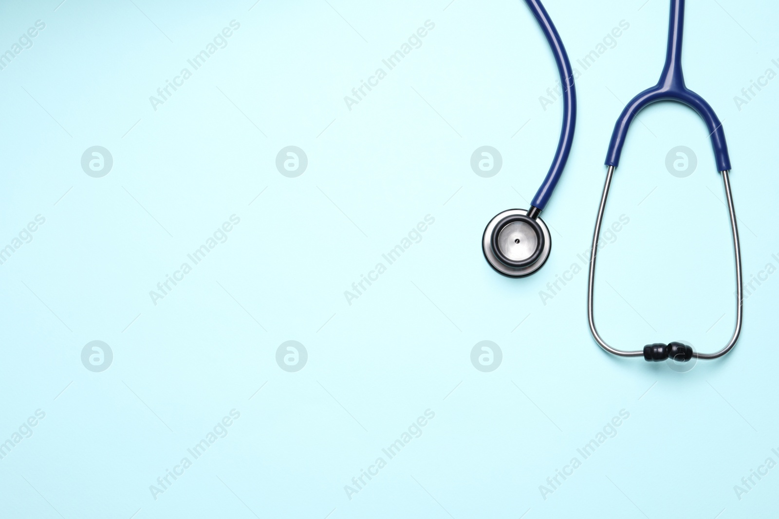 Photo of Stethoscope on light blue background, top view. Space for text