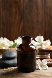 Beautiful composition with jasmine essential oil and fresh flowers on wooden table