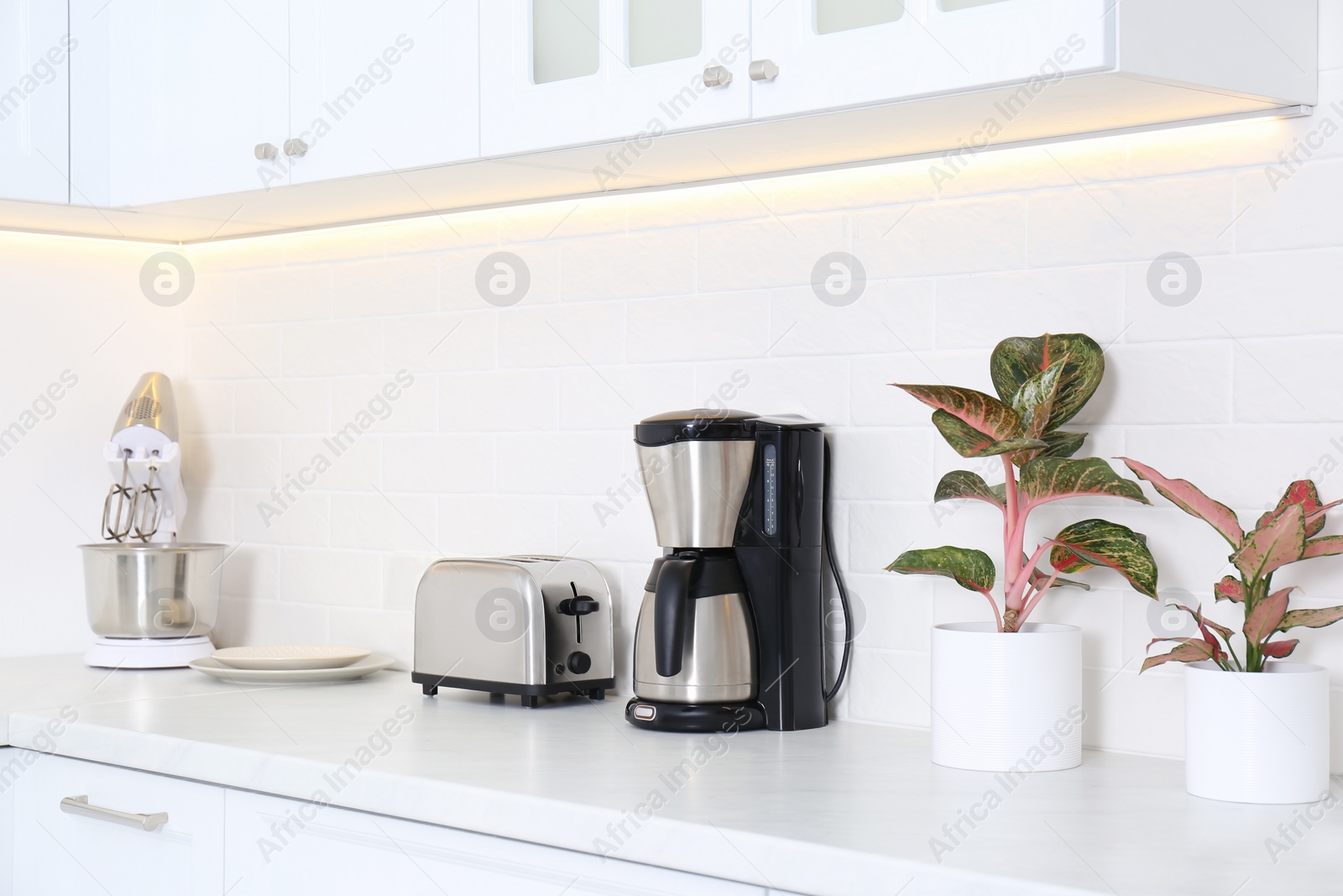 Photo of Modern toaster and household appliances on counter in kitchen