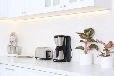 Photo of Modern toaster and household appliances on counter in kitchen