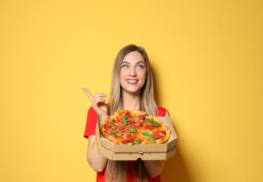 Attractive young woman with delicious pizza on color background