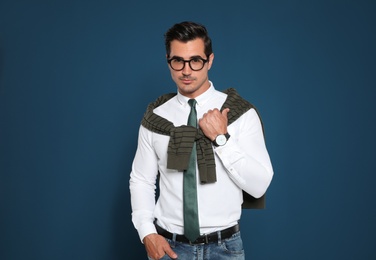 Portrait of handsome young man wearing glasses on blue background