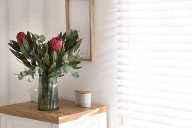 Vase with beautiful Protea flowers on table indoors