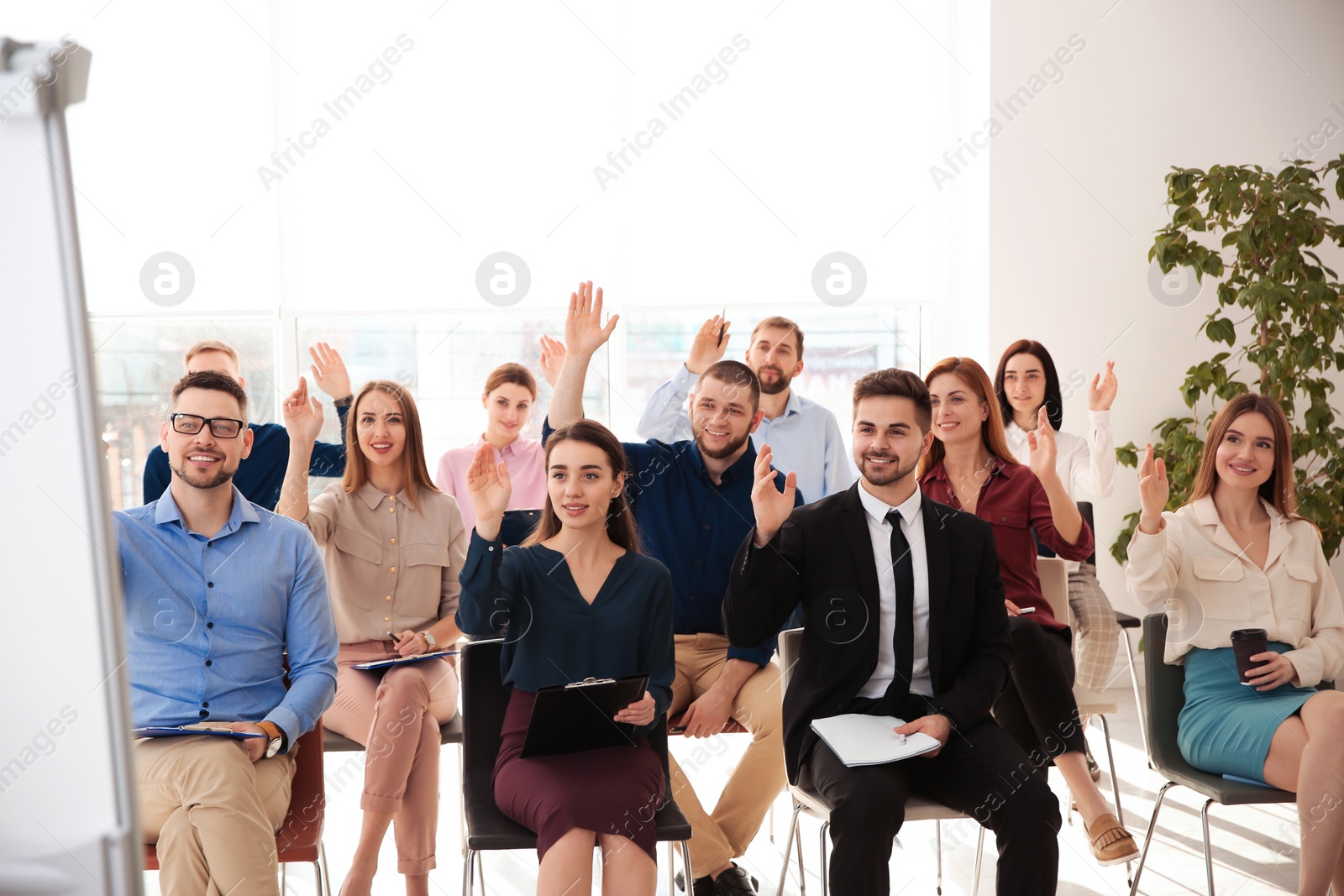 Photo of People raising hands to ask questions at business training indoors