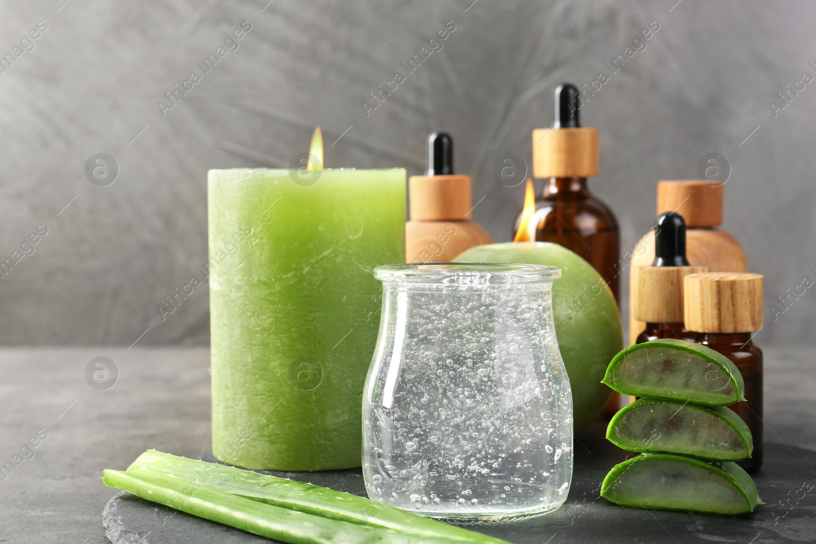 Photo of Cosmetic products, burning candles, aloe vera leaves and gel on table