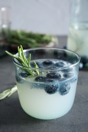 Photo of Glass of refreshing blueberry cocktail with rosemary on table