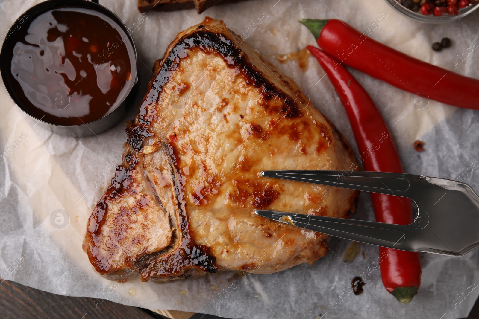 Photo of Tasty grilled meat, chili and marinade on wooden table, top view