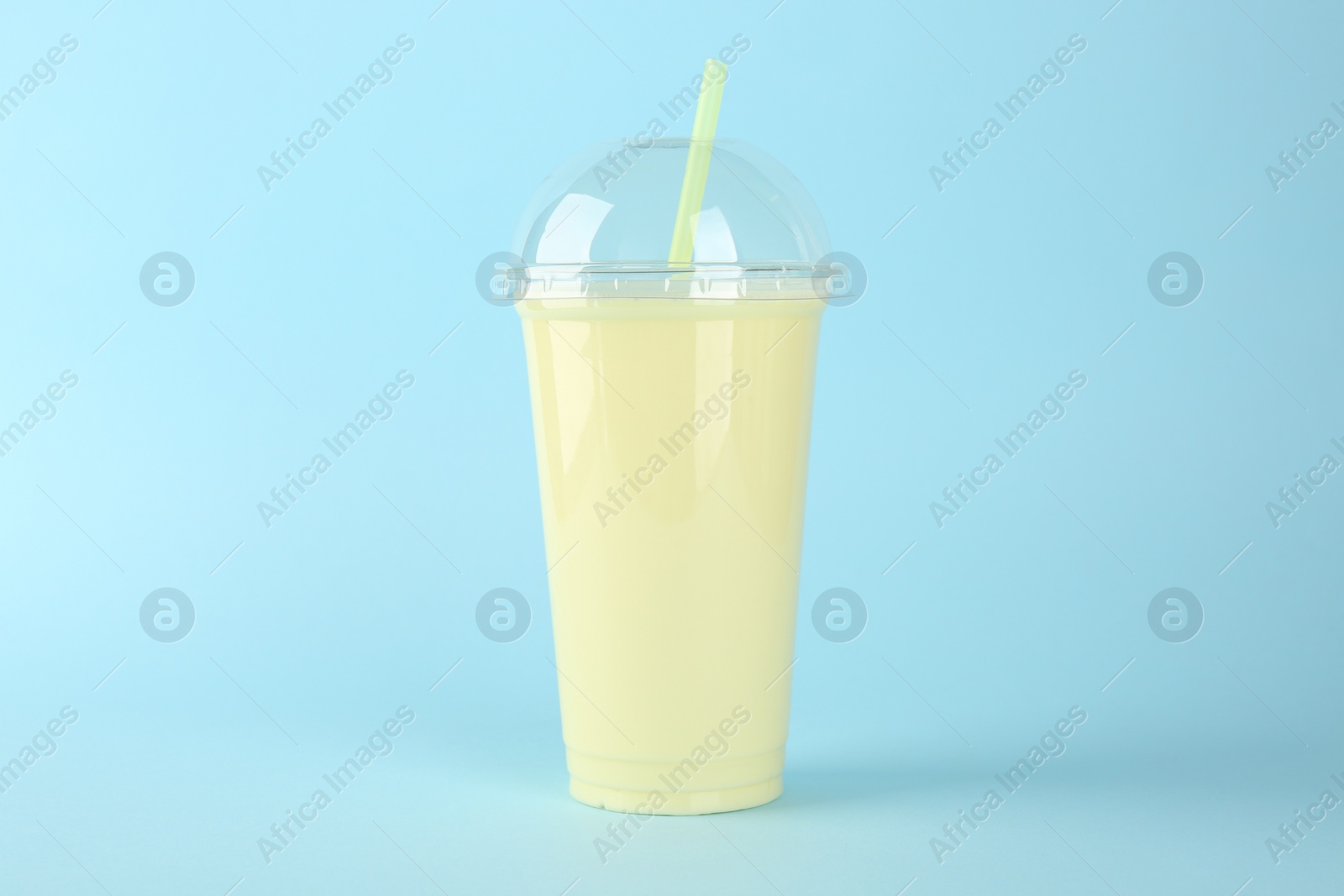 Photo of Plastic cup of tasty smoothie on light blue background