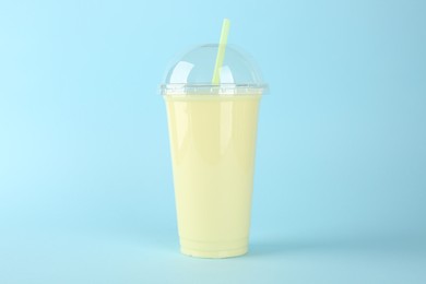 Plastic cup of tasty smoothie on light blue background