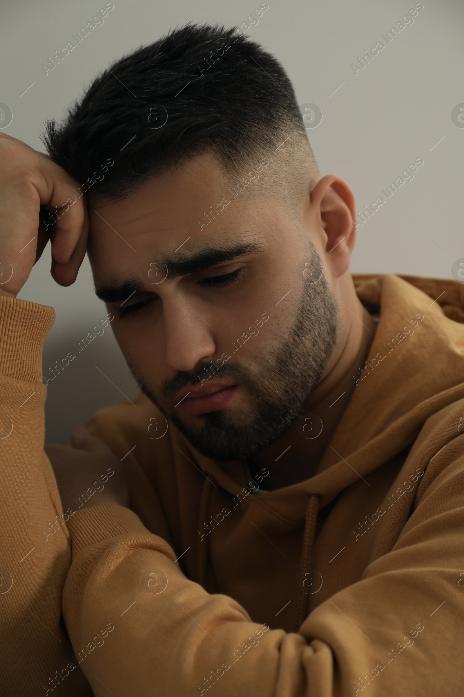 Photo of Sad young man in hoodie at home