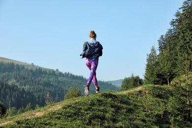Photo of Young woman running on mountain trail in summer