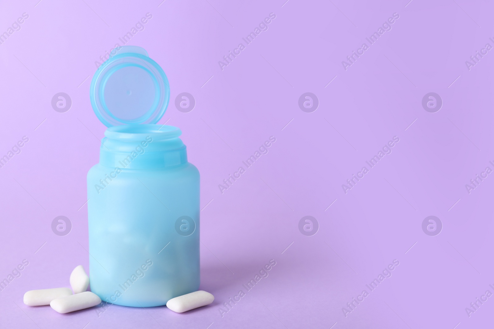 Photo of Jar with chewing gums on lilac background. Space for text